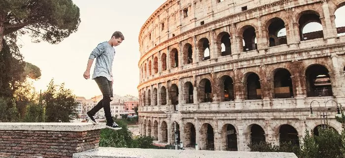 A man walking in front of the Coliseum in Rome