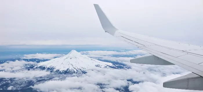 A silver plane wing and a snow capped mountain