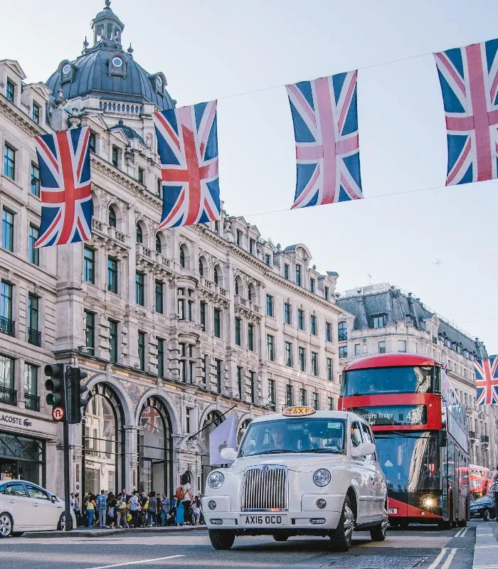 A London taxi and double decker red bus under union jack flags