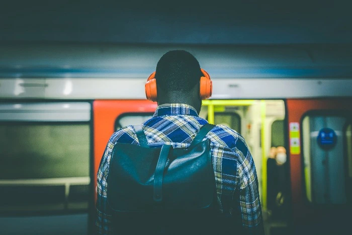A man wearing headphones in front of a London tube train