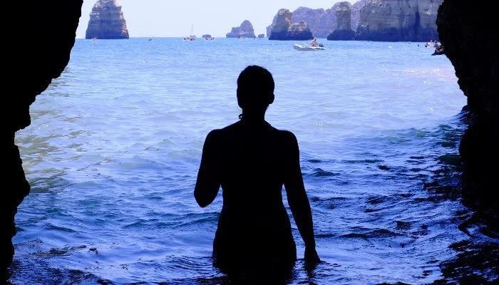 The outline of a woman standing in water in a blue cave