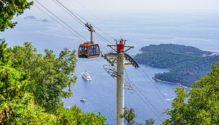 A red cable car going up a mountain 