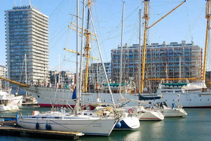 Ships in a harbor with tall buildings in the distance in Ostend