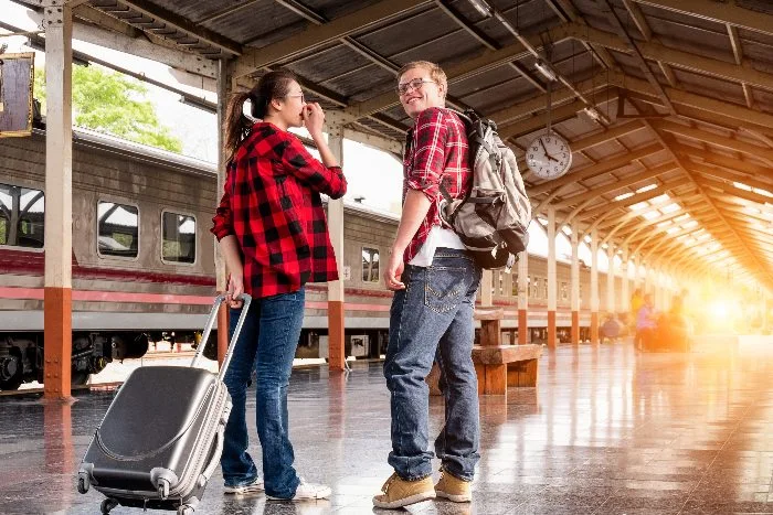 A couple wearing red flannel shirts standing on a train platform  