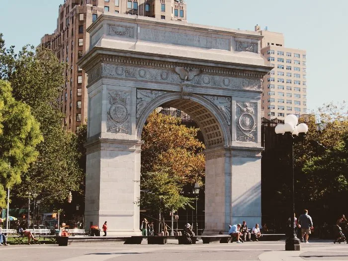 people sit in front of the Washington Square Arch in Greenwich Village