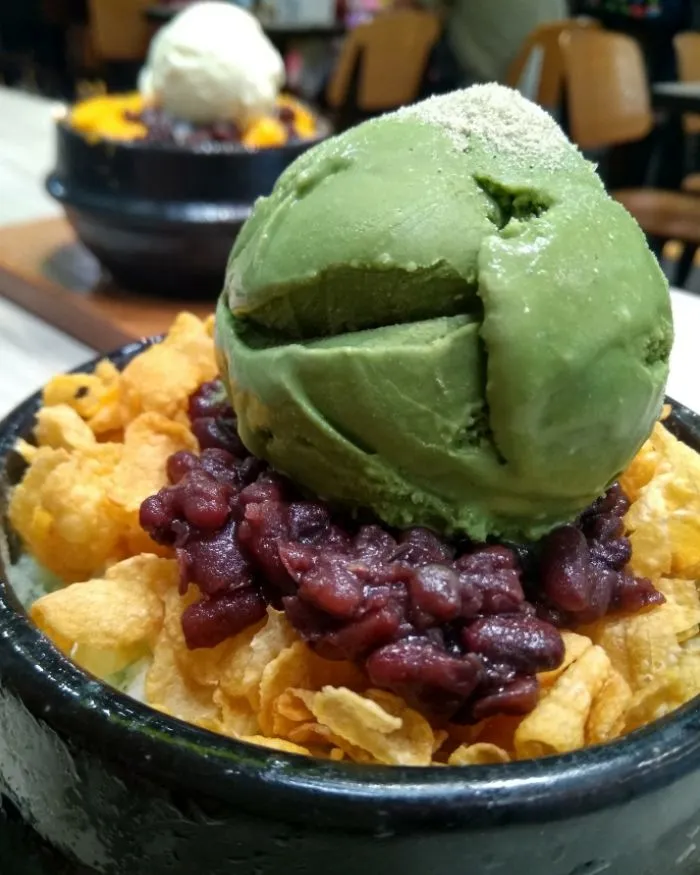 A scoop of green pitbingsoo ice cream on orange crisps