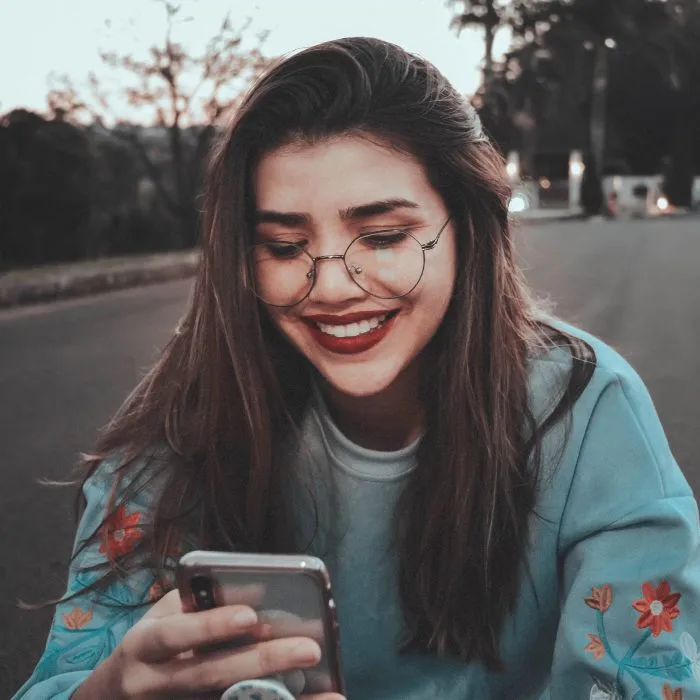 A smiling woman looking at a mobile phone