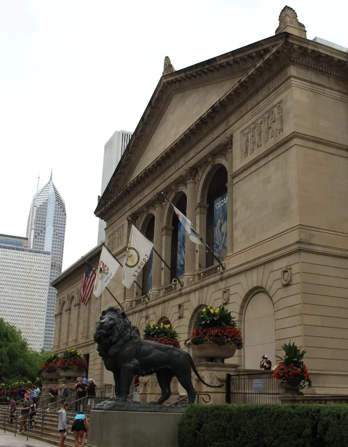 A lion statue sits and steps in front of the Art Institute of Chicago
