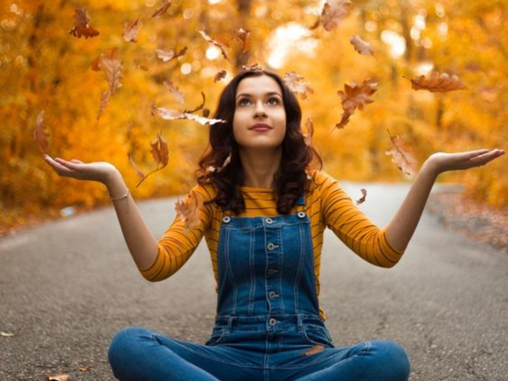 Yellow leaves fall on a woman in overalls