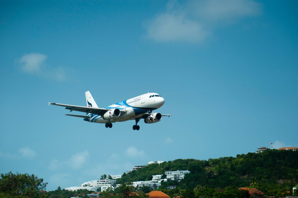 A white plane preparing to land in a tropical location. 