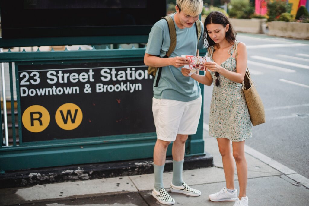 A couple who is looking at a brochure in the streets of Downtown Brooklyn, exploring the city.