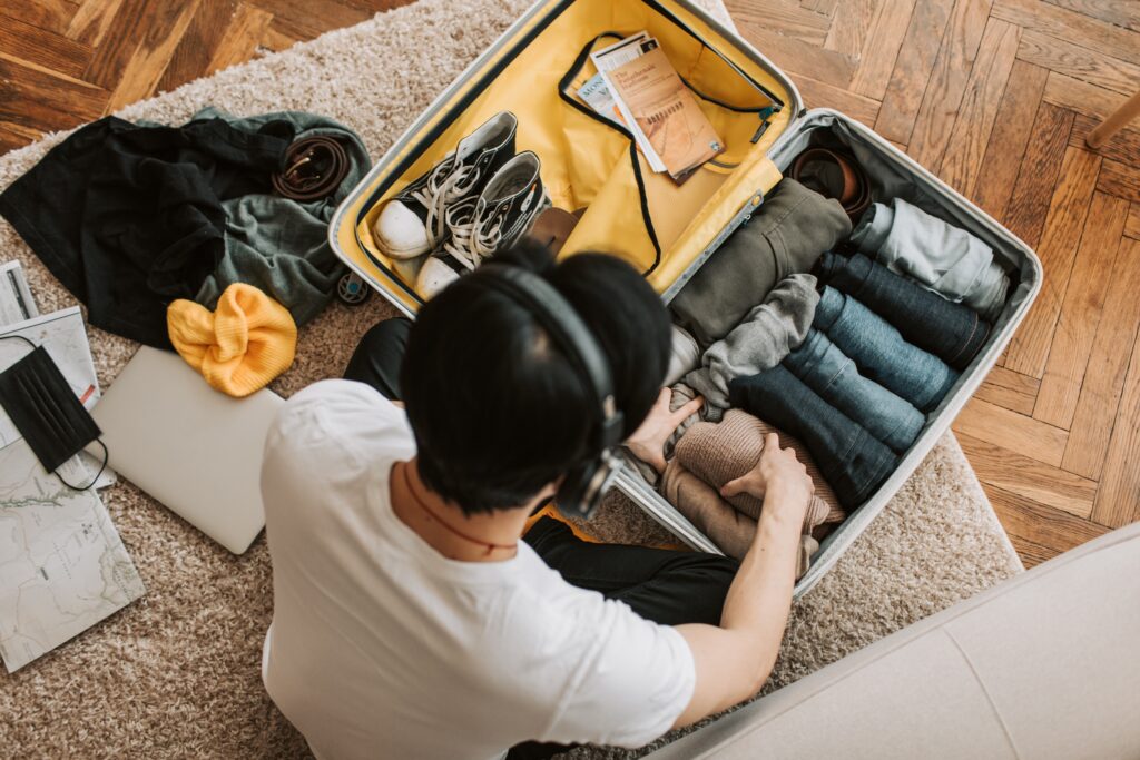 A young adult that is packing his suitcase carefully, he is trying to save as much space as possible in order to pack more items.