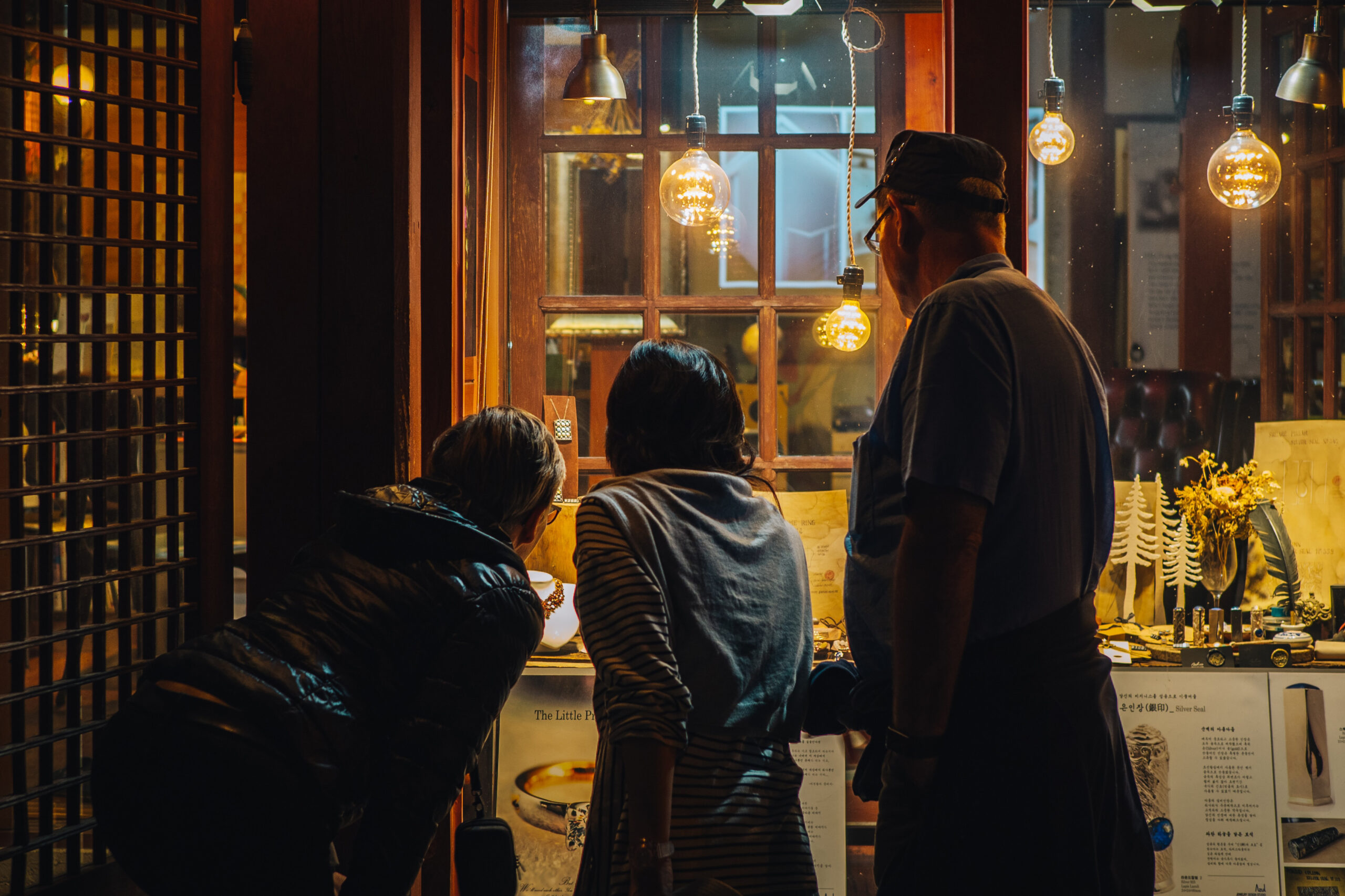Curious onlookers exploring a traditional Korean handicraft shop at night, illuminated by warm, inviting lights.