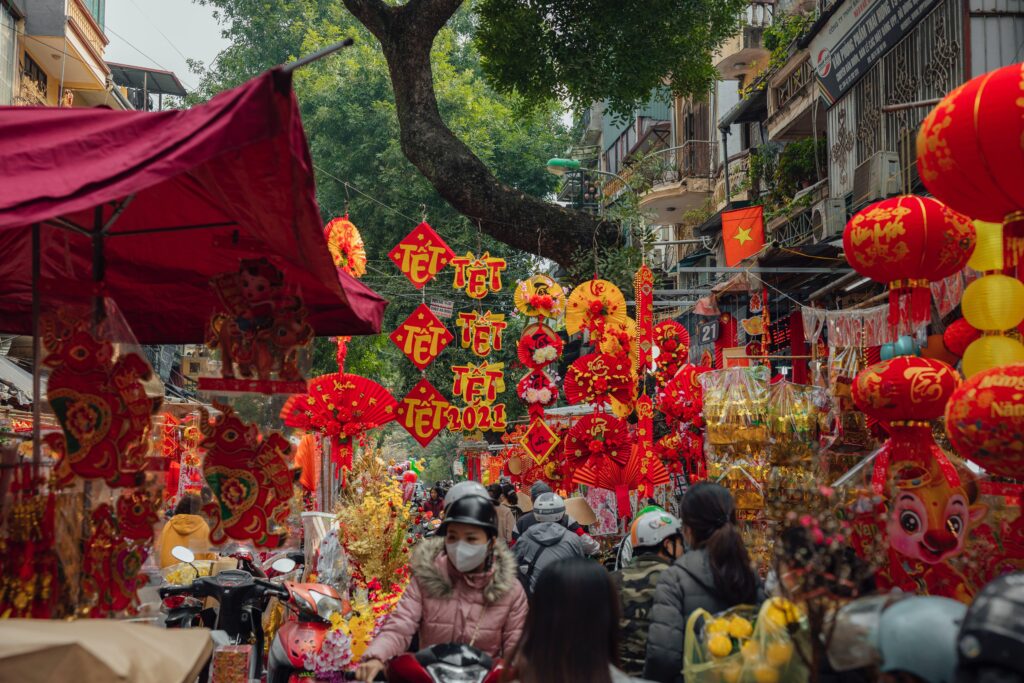 Lunar New Year decorations at a bustling market in Vietnam, showcasing red lanterns and cultural ornaments, a potential travel destination for students seeking cultural experiences.