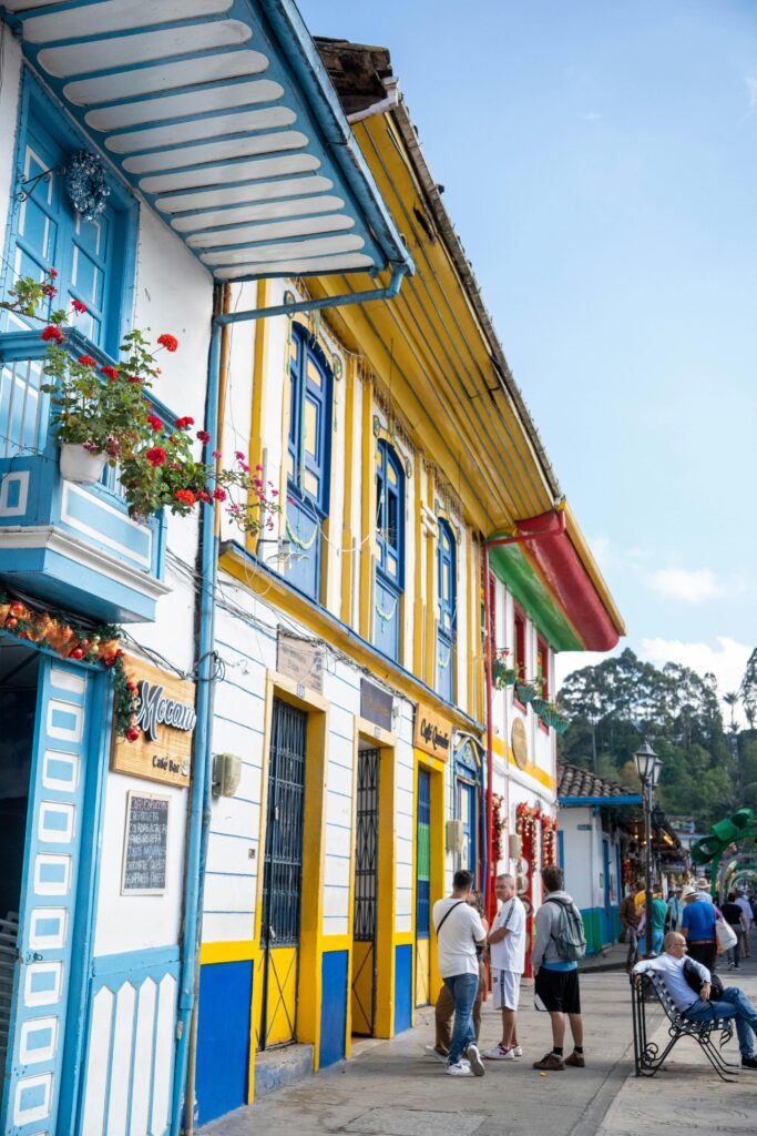 Colorful colonial architecture lining a lively street in a Latin American town, with locals and tourists mingling, epitomizing the vibrant community and cultural immersion sought by young travelers during a gap year or educational trip.