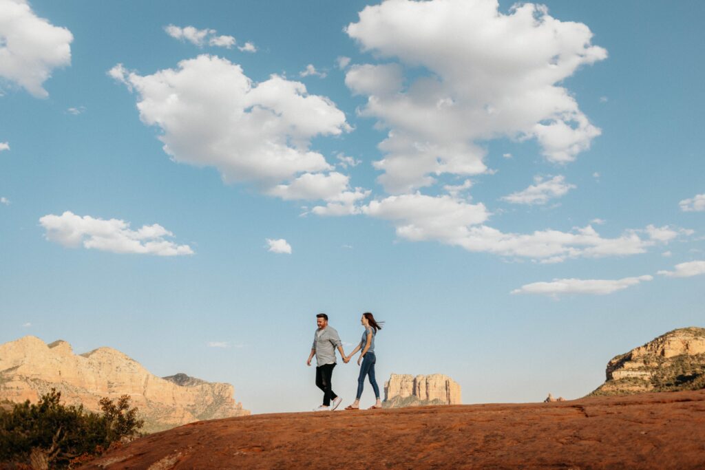 A young couple holding hands on a scenic hike through the Arizona desert, a perfect adventurous getaway for students.