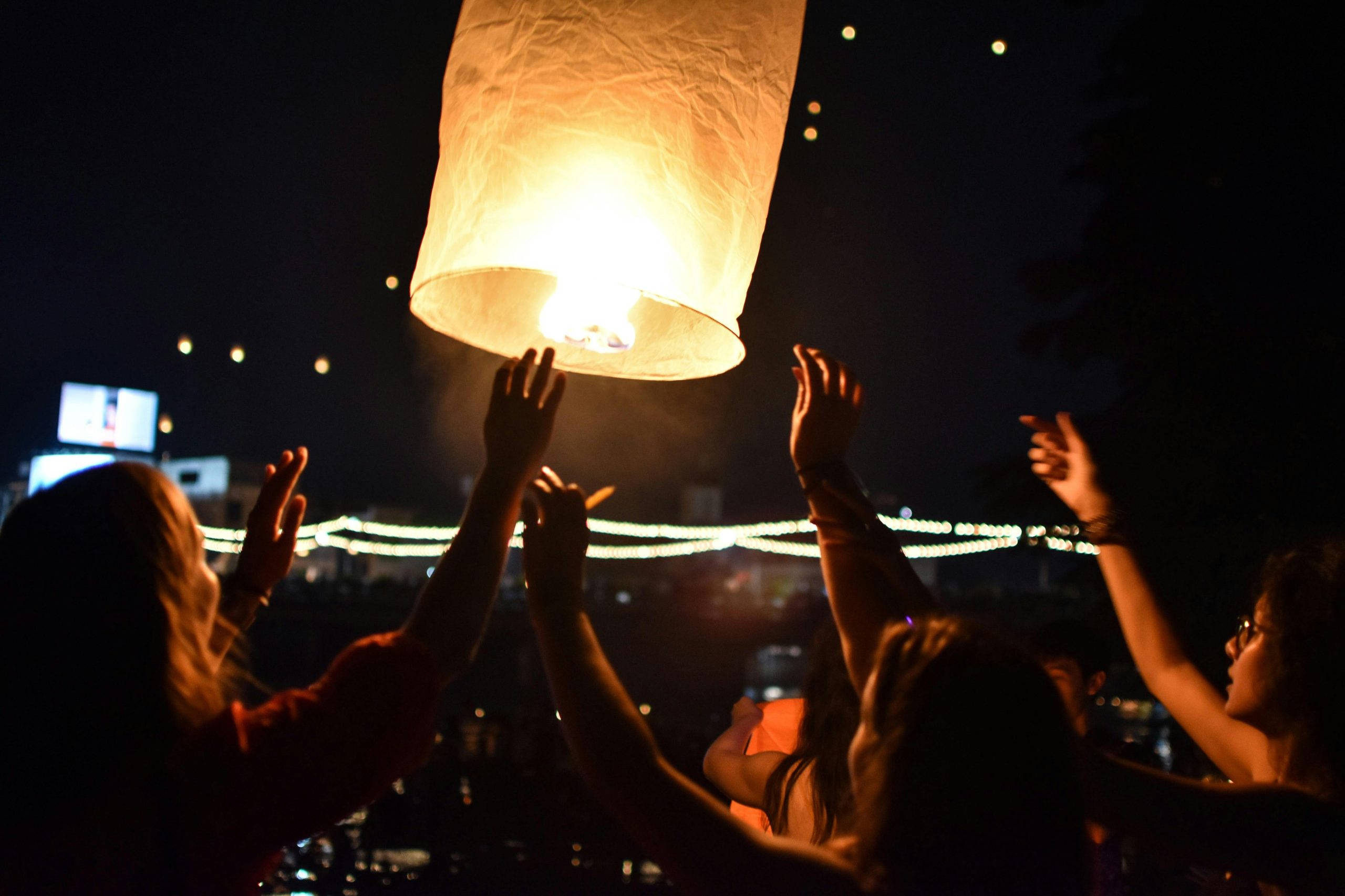 People letting a floating lantern off into a night sky!
