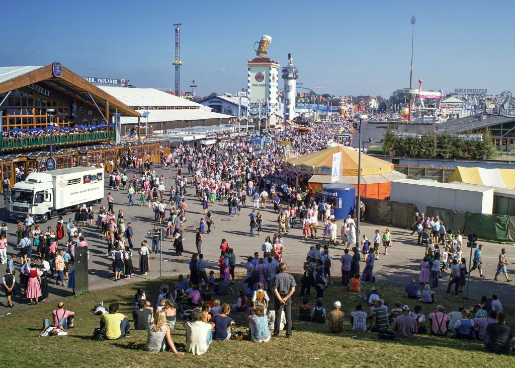 Crowds at Munich Oktoberfest on Theresienwiese with Paulaner beer tower and tents.