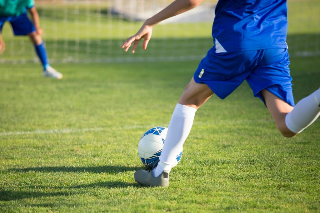 Young soccer player dribbling during a match on a grass field